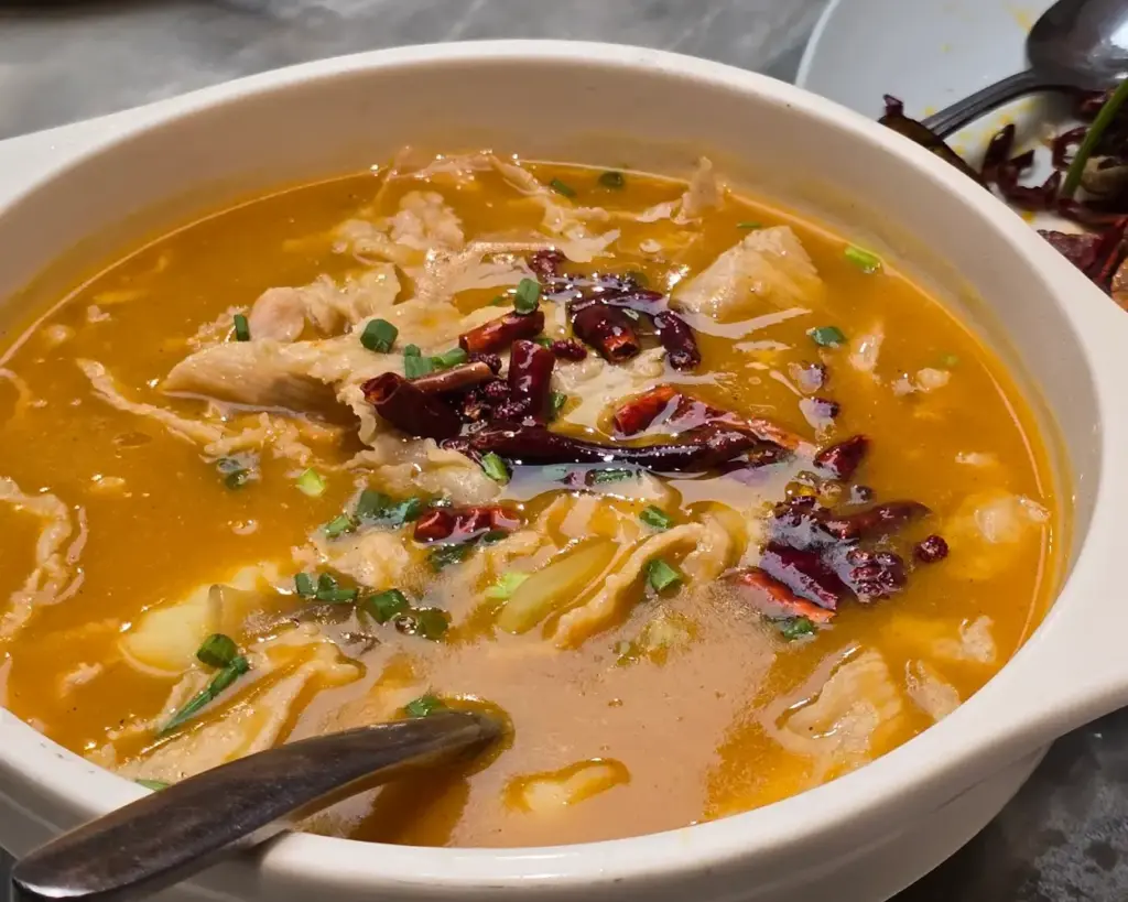 A warm bowl of braised fish maw in a thick, flavourful gravy, often paired with mushrooms and vegetables, showcasing a luxurious and comforting texture.