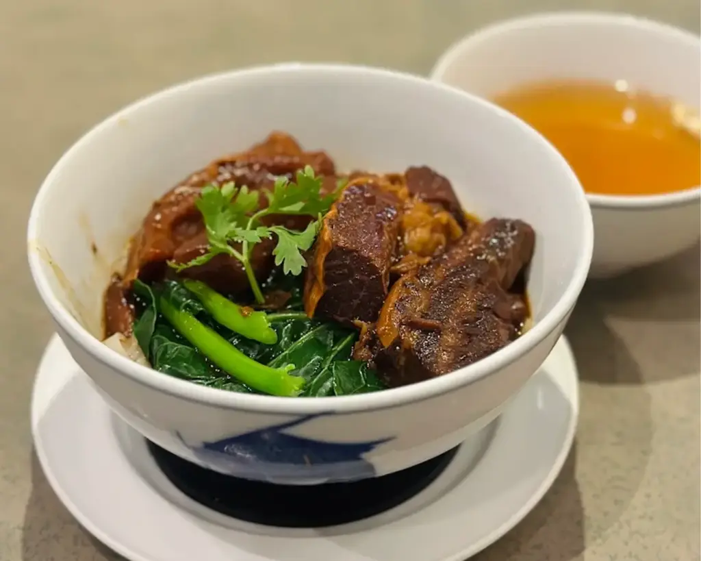 A bowl of tender, slow-cooked meat paired with fresh vegetables in a savoury sauce, creating a balanced and wholesome dish.