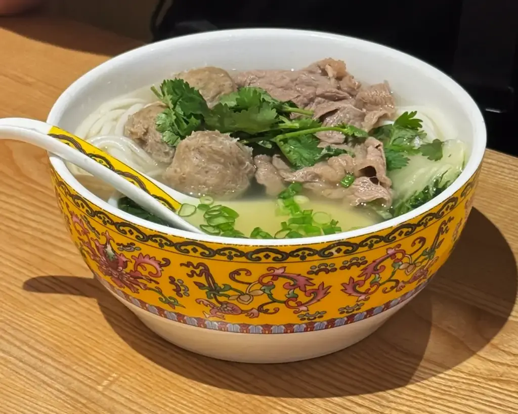 A satisfying serving of noodles topped with generous portions of meat, vegetables, and sauce, presented in a casual dining style.