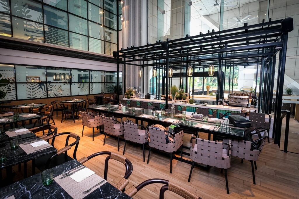 A cafe on Orchard Road, Singapore, featuring tables and chairs arranged in a spacious interior of a large building.
