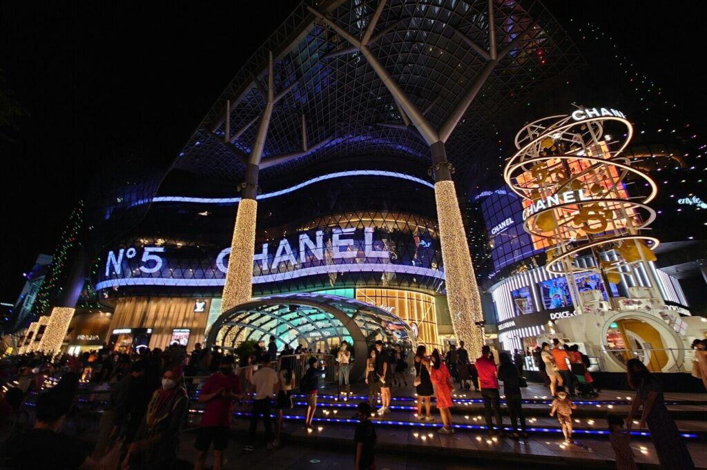 People crowd outside Ion Orchard Mall, creating a lively scene in front of the popular shopping destination.