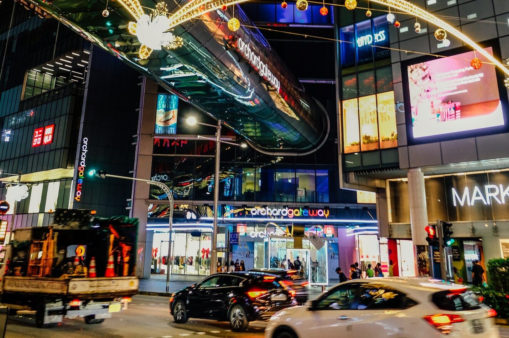 Orchard Road, Singapore, showcasing a lively street scene with cars and people walking along the busy thoroughfare.