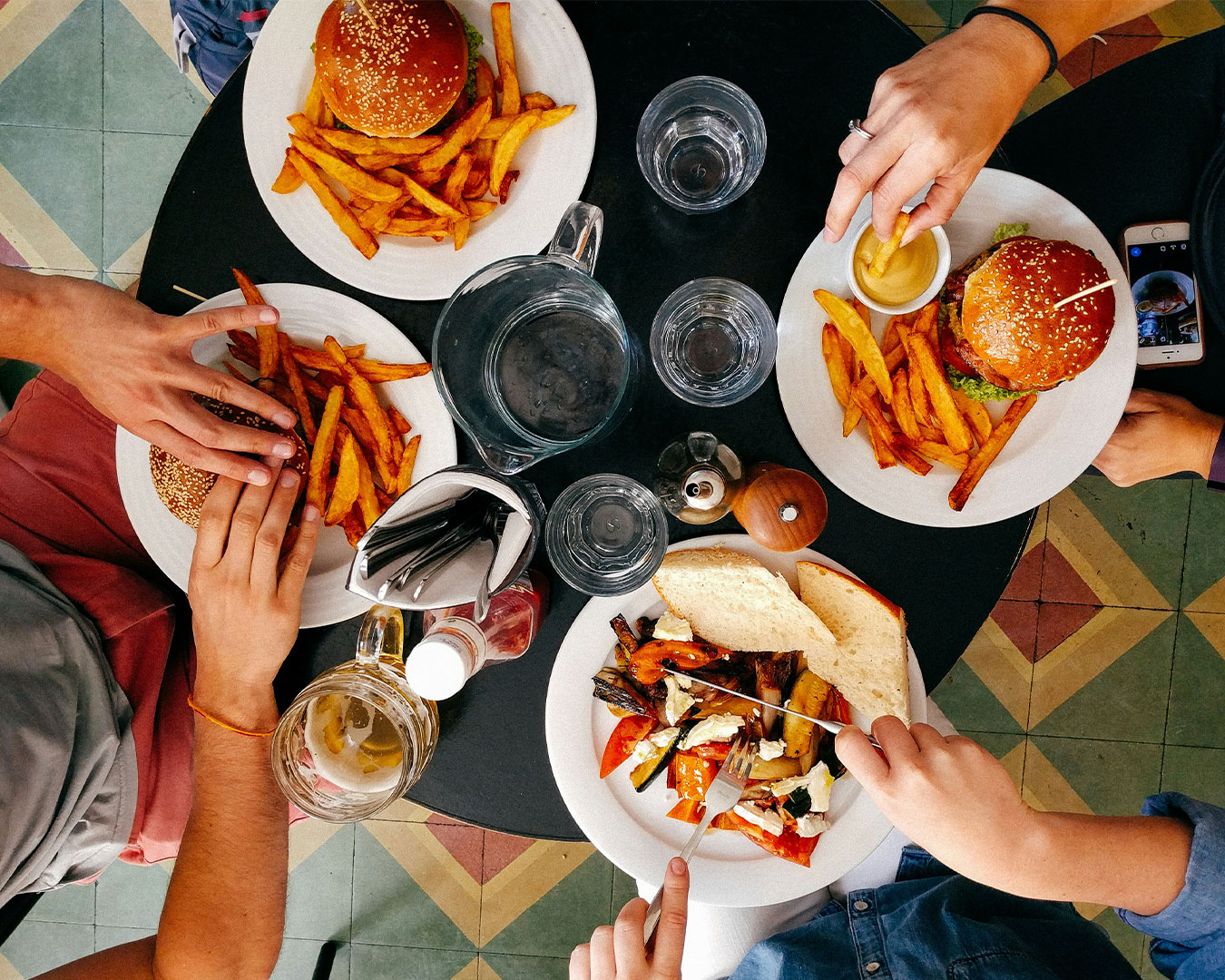 A cheerful group of friends sitting around a dining table, sharing and enjoying various dishes together, creating a lively and social atmosphere.