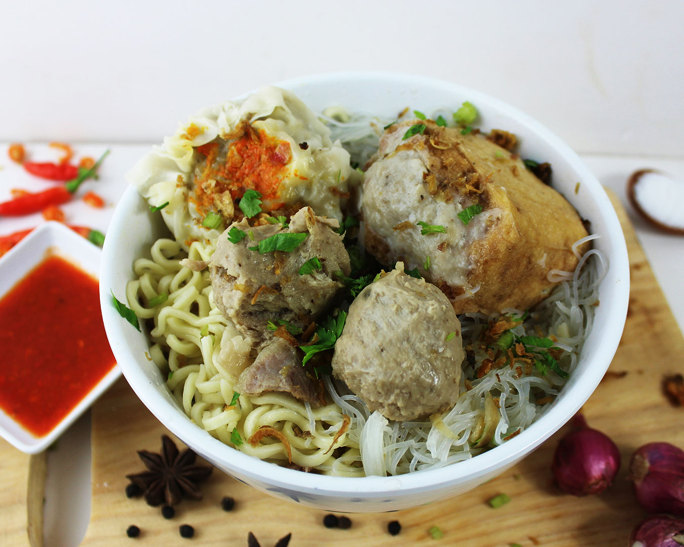A steaming bowl of Indonesian meatball soup, garnished with fresh herbs, served in a white bowl, ready to be savoured.