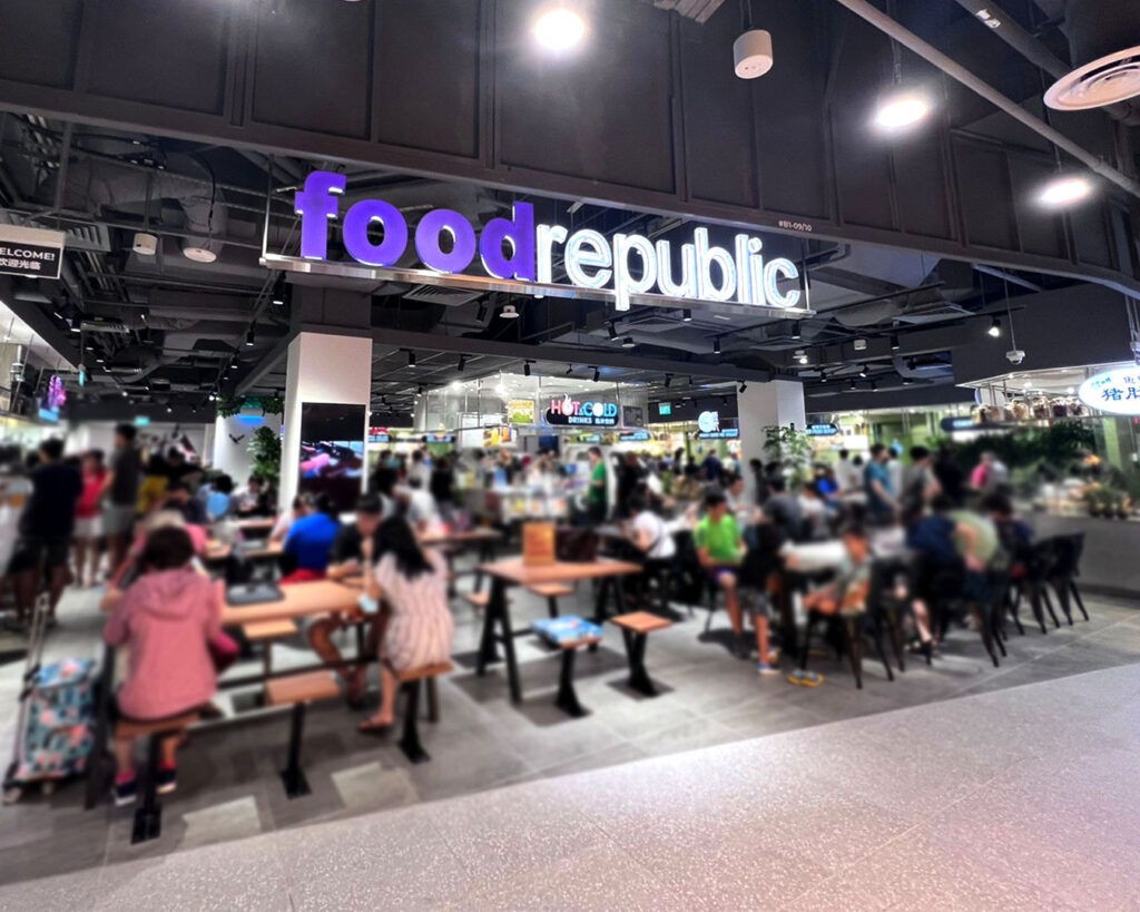 Interior of Food Republic at 313 Somerset, featuring rows of food stalls, bright menu boards, and diners seated in a lively, casual food court environment