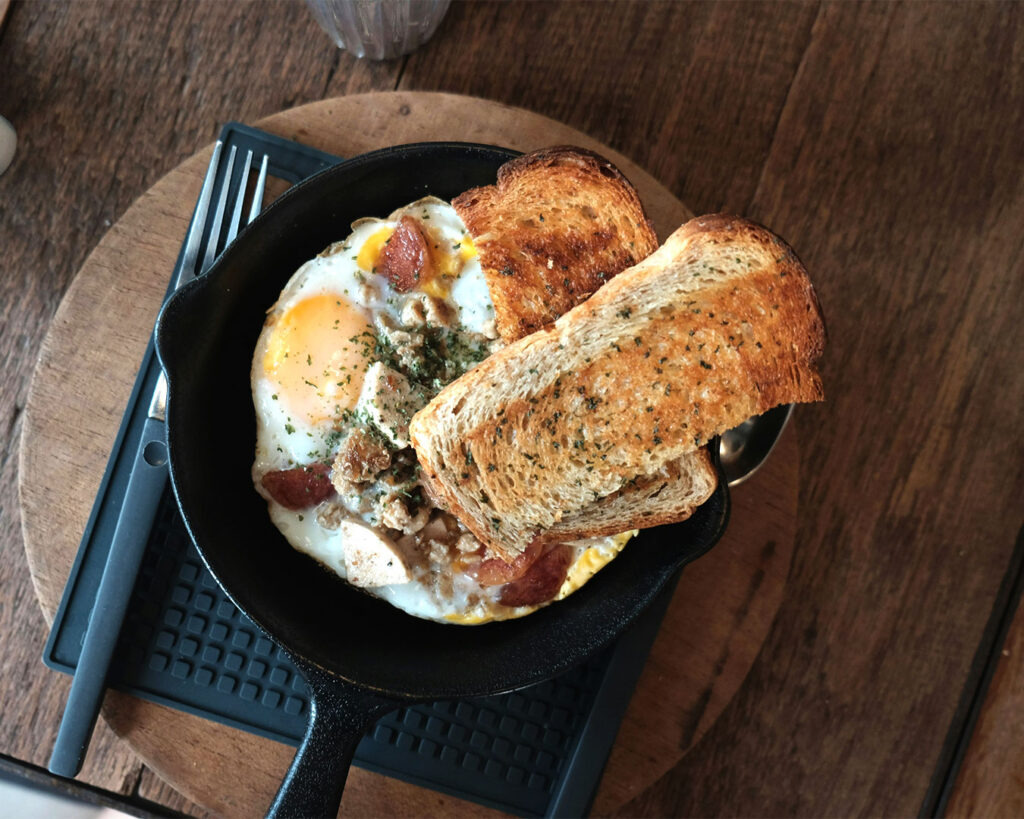 A breakfast plate with toasted bread and a sunny-side-up egg, served with simple garnishes on a clean dining table.