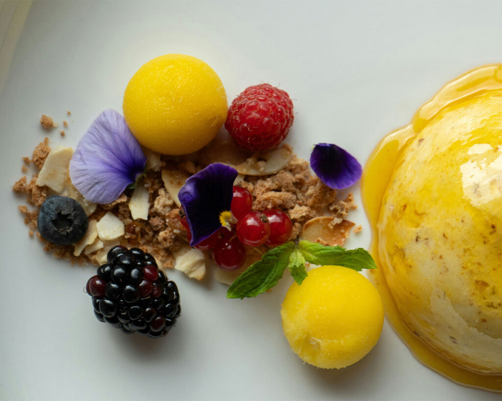 An elegant dessert plated with precision, featuring layered textures and decorative elements, finished with sauce and garnish to create a visually refined fine-dining finale.