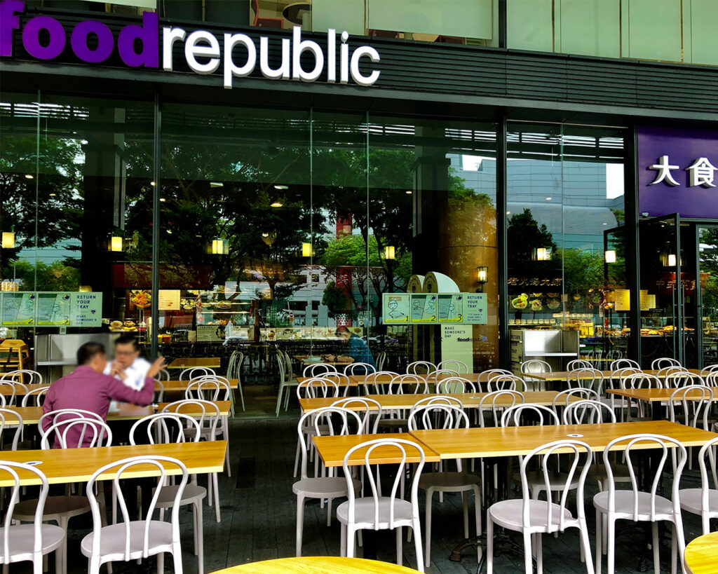 The bustling interior of 313 Somerset Food Court, with various food stalls and people walking around, capturing a vibrant city dining scene.
