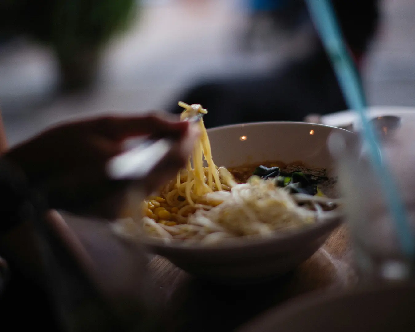 Close-up of chopsticks lifting a portion of noodles from a bowl, showing the texture from the freshly prepared dish