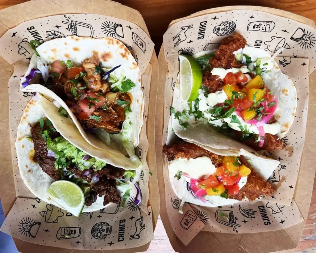 Two sets of freshly prepared tacos served on plates at a dining spot in 313@Somerset Orchard mall, filled with vibrant ingredients such as seasoned meat, fresh vegetables, and colourful toppings.